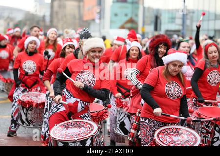 Manchester, Regno Unito. 3 dicembre 2023. La parata natalizia di Manchester è in corso per le strade della città, con tutti i personaggi abituali come Babbo Natale e gli elfi della vita reale. Una Pipe band e un gruppo di batteristi Salva forniscono alcuni dei suoni con le famiglie che fiancheggiano le strade per dare un'occhiata ad alcuni dei burattini giganti e al globo a grandezza naturale con Snow Queen. Manchester, Regno Unito. Foto Stock