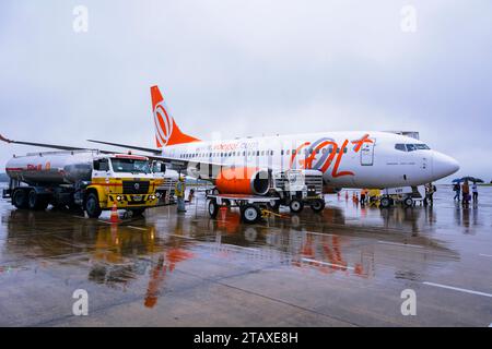 Foz do Iguaçú, Paraná, Brasile. Boeing 737 700 in fase di rifornimento. I passeggeri sbarcano con ombrelloni in un giorno di pioggia a Foz do Iguazú Foto Stock