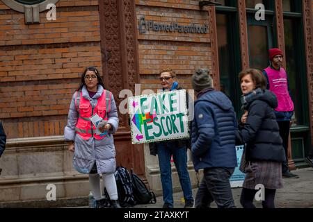 NEW York, NEW YORK - 2 DICEMBRE: Un attivista per i diritti dell'aborto tiene un cartello "Fake Escort" accanto a un avvocato anti-aborto mascherato come un lavoratore di Planned Parenthood nel tentativo di dissuadere i pazienti dal ricevere cure il 2 dicembre 2023 a New York City. (Foto di Michael Nigro/Sipa USA) credito: SIPA USA/Alamy Live News Foto Stock