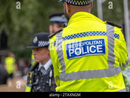 Cartello della polizia metropolitana sul retro di una giacca ad alta visibilità indossata dagli agenti di polizia che monitorano una manifestazione di protesta in strada attraverso Londra. Foto Stock