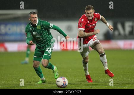 Michael Smith di Yeovil Town (a sinistra) e James McClean di Wrexham si battono per il pallone durante la partita del secondo round della Emirates fa Cup all'ippodromo di Wrexham. Data immagine: Domenica 3 dicembre 2023. Foto Stock