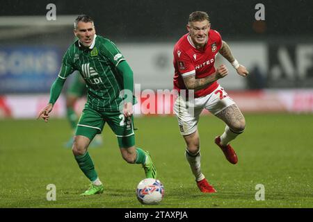 Michael Smith di Yeovil Town (a sinistra) e James McClean di Wrexham si battono per il pallone durante la partita del secondo round della Emirates fa Cup all'ippodromo di Wrexham. Data immagine: Domenica 3 dicembre 2023. Foto Stock