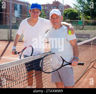 Nonno e nipote in posa sul campo da tennis Foto Stock