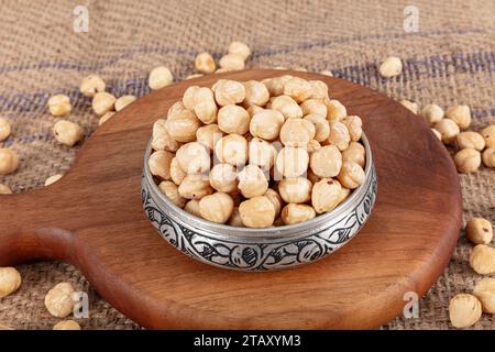 Varietà di nocciole in ciotola di rame su fondo di lino. Nocciole tostate sgusciate, nocciole sgusciate e nocciole tostate senza guscio. Cibo sano conc Foto Stock