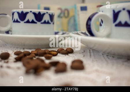 grani di caffè e tazze di caffè e venti banconote da euro. Concetto, l'aumento del prezzo del caffè Foto Stock