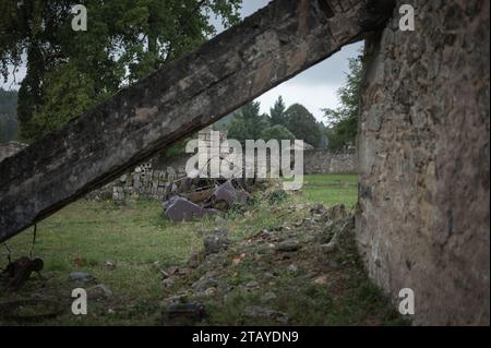 Dettaglio dei resti di una vecchia auto distrutta durante la guerra e di una casa demolita con la trave caduta Foto Stock