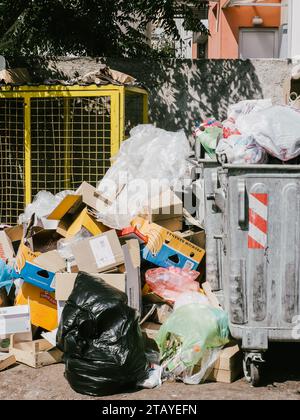 Budva, Montenegro - 05 agosto 2023: Scatole di cartone vuote e rifiuti di plastica si trovano accanto a un cestino di spazzatura che trabocca Foto Stock