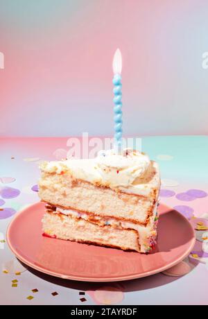 Una fetta di crema al burro di vaniglia, torta di compleanno bianca a due strati con candele accese su uno sfondo morbido e pastello Foto Stock