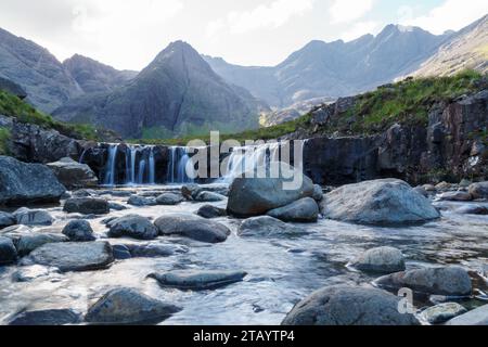 Cascate di piscine favolose e montagne lontane nell'Isola di Sky in Scozia. Una serie di rocce è sparsa in tutta la piscina. Foto Stock