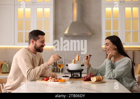 Coppia affettuosa che si gode la fonduta durante un appuntamento romantico in cucina Foto Stock