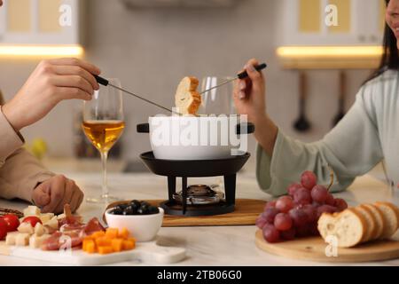 Coppia che si gode la fonduta durante un appuntamento romantico in cucina, primo piano Foto Stock