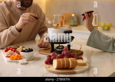 Coppia che si gode la fonduta durante un appuntamento romantico in cucina, primo piano Foto Stock