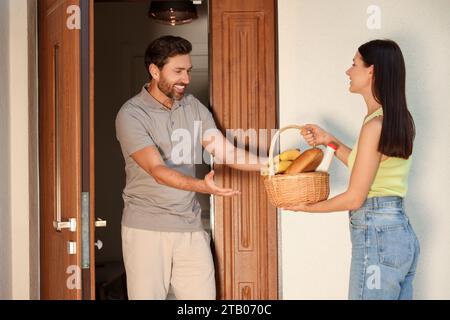 Rapporto amichevole con i vicini. Giovane donna con cesto di vimini di prodotti che trattano l'uomo all'aperto Foto Stock