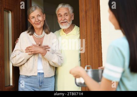 Rapporto amichevole con i vicini. Giovane donna con pentola in visita a coppie anziane Foto Stock