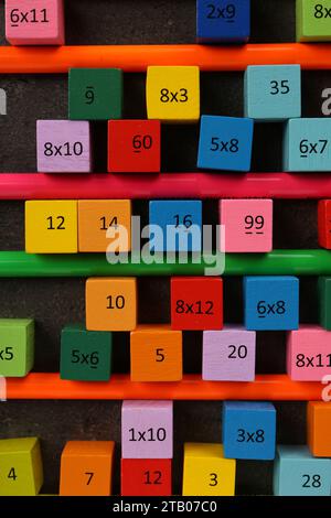 Molti cubi colorati con numeri, moltiplicazioni e matite su tavola grigio scuro, piatto Foto Stock