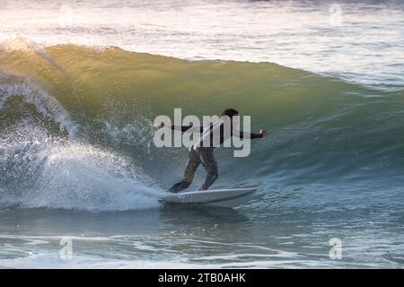 Giovane surfista con muta che si gode grandi onde. Foto Stock