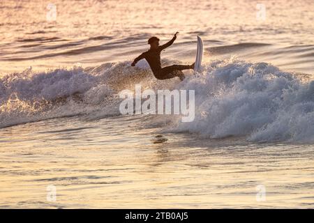 Giovane surfista con muta che si gode grandi onde. Foto Stock