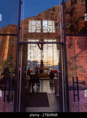 Persone all'interno della famosa Cappella della Santa Croce con roccia rossa e cielo blu riflessi nelle porte d'ingresso della finestra di vetro. Sedona, Arizona sud-ovest degli Stati Uniti Foto Stock