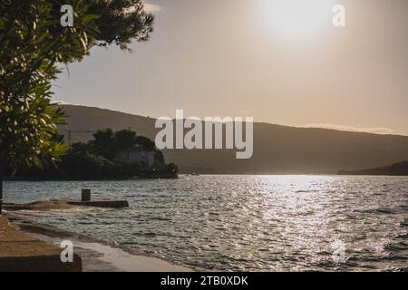 Bel tratto di spiaggia artificiale vicino alla città di Cherso, Croazia, guardando verso est e l'alba. Calma autunnale al mare. Foto Stock