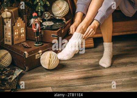 Primo piano dei piedi femminili in calze di Natale bianche. Festa di Capodanno, Natale. Dischi in vinile Foto Stock