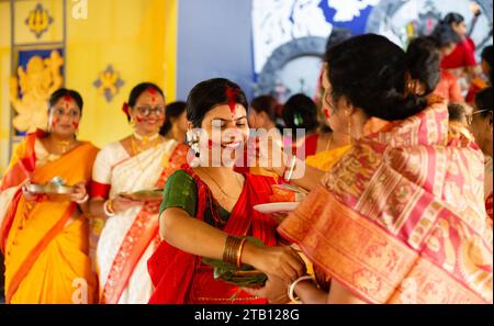 Birbhum, Bengala Occidentale, India - 24 ottobre 2023: Una bella donna in abito tradizionale con faccia sorridente di colore rosso che gioca con sindoor durante l'ultimo Foto Stock