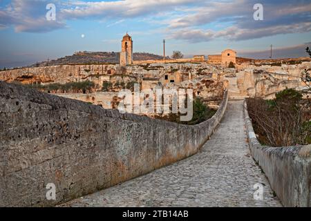 Gravina in Puglia, Bari, Italia: Paesaggio all'alba dall'antico ponte dell'acquedotto della vecchia chiesa rupestre e le case rupestri scolpite nel tufo Foto Stock
