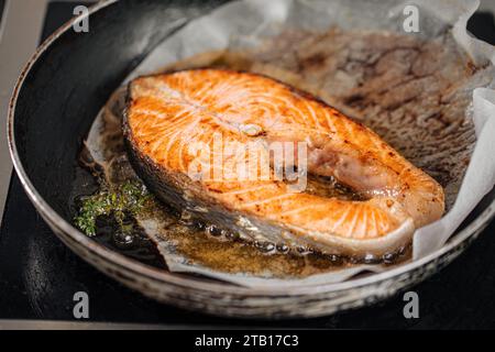 Friggere la bistecca di salmone su carta pergamena con burro Foto Stock