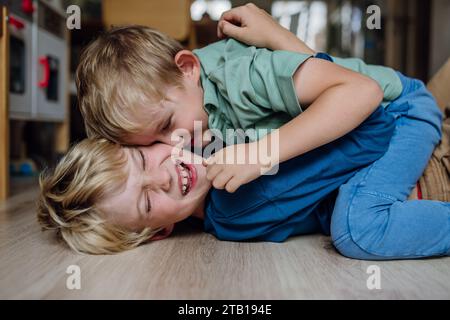 Due ragazzini che lottano per terra, fratelli che si divertono a casa. Concetto di relazione tra fratelli e amore fraterno. Foto Stock