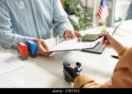 Primo piano del gestore del centro visti che prende i documenti dal cliente durante la riunione in ufficio Foto Stock