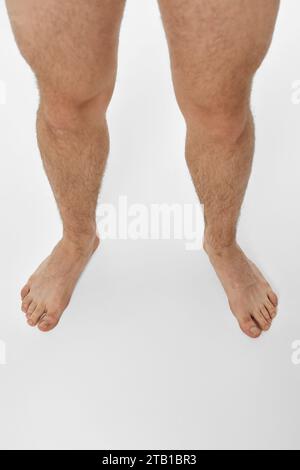 Gambe maschili scalzi su sfondo bianco. vista dall'alto Foto Stock