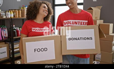 Giovani volontari sorridenti insieme, con in mano pacchi di cartone pronti a donare al centro di beneficenza, simboleggiando l'unità e il portare Foto Stock