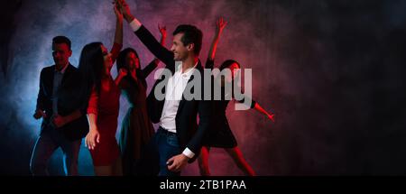 Allegro e divertente gruppo di amici o colleghi mentre festeggiano e ballano, bevono champagne o vino alla festa di Natale o alla vigilia di Capodanno. Corpo Foto Stock