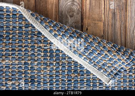 Tappeto in denim geometrico intrecciato a mano su pavimento in legno. Foto Stock