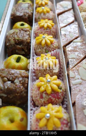 Assortimento indiano di dolci Diwali o mithai con diya e fiori. Idea regalo natalizia. Kaju katli, peda di frutta secca, barfi, barfi di anacardi, marzapane. Foto Stock