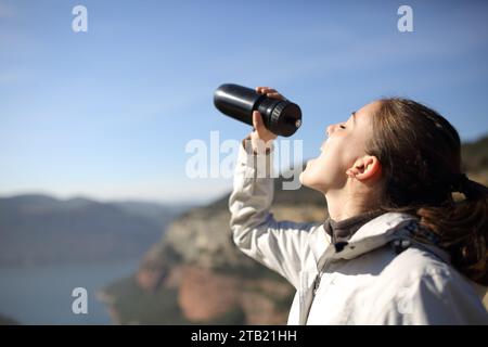 Escursionista che beve da una bottiglia in piedi nella natura Foto Stock