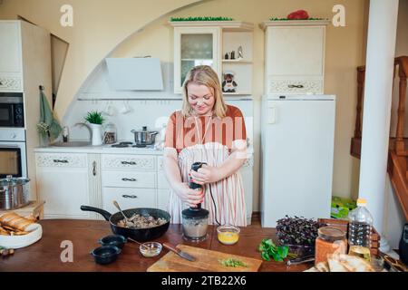 Donna cuoca a casa in cucina preparando cibo delizioso Foto Stock