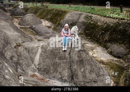 La giovane ragazza cammina con un cane Samoyed bianco e soffice in natura Foto Stock