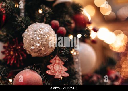 Palline di Natale lucide color rosso argento e giocattoli appesi su un albero di Natale con magiche luci ghirlande. Rami di abete rosso decorati. Foto Stock