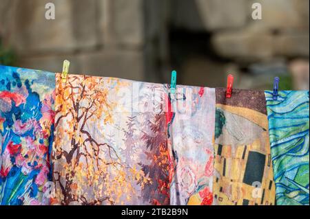 Tessuti colorati appesi a una linea di abbigliamento in un mercato all'aperto. Foto Stock