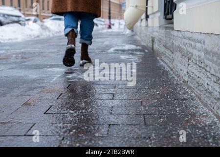 Grani di sale tecnici sulla superficie del marciapiede ghiacciato in inverno, utilizzati per sciogliere ghiaccio e neve Foto Stock