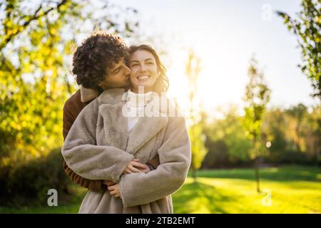 Felice coppia amorevole che si abbraccia e si bacia nel parco al tramonto. Foto Stock