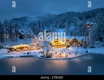 Vista aerea delle case illuminate nel villaggio innevato di notte Foto Stock