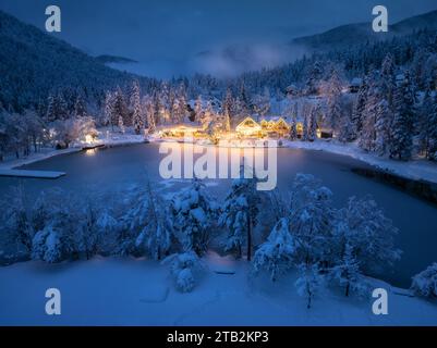 Vista aerea delle case illuminate nel villaggio innevato di notte Foto Stock