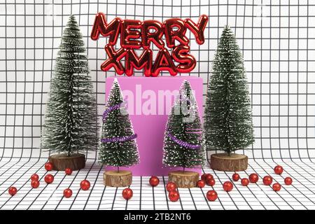 Un decoro natalizio di plastica rosso lucido con un testo che dice allegri natali con bauble di natale rosso e una scena forestale in miniatura composta da diversi elementi Foto Stock