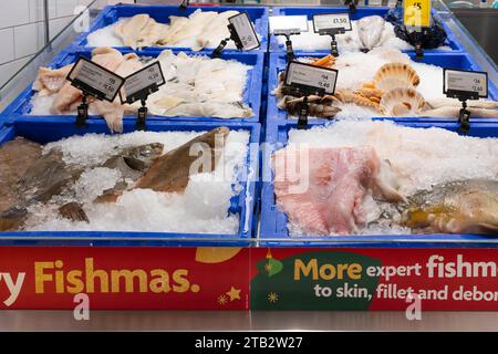 Banco di pesce fresco al supermercato Morrisons con ali di razze, passera di mare intera, sogliola al limone e capesante in vendita. REGNO UNITO Foto Stock