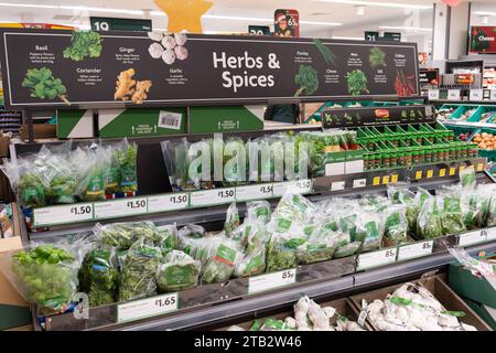 Le erbe e le spezie sono esposte con i prezzi delle erbe fresche in confezioni e vasetti e un cartello pubblicitario sopra in un supermercato Morrisons, Regno Unito Foto Stock