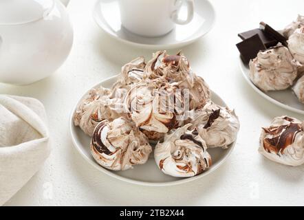 Meringa al cioccolato con tè su fondo bianco. Vista ravvicinata Foto Stock