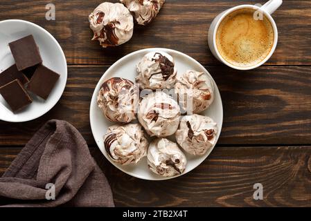 Meringa al cioccolato e tazza di caffè su fondo di legno. Vista dall'alto, base piatta Foto Stock