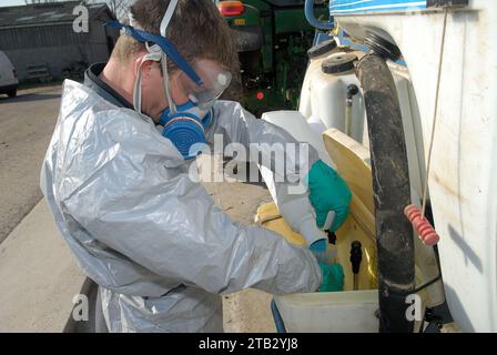 Agricoltura e uso di prodotti chimici. Trattamento fitosanitario in un'azienda agricola: Agricoltore dotato di protezione personale, tra cui tute, maschere e gog Foto Stock