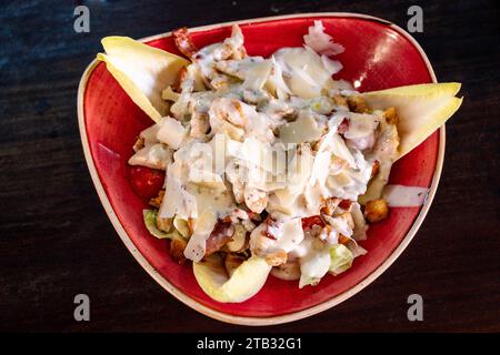 Una vista a volo d'uccello su un'insalata Caeser di gamberi servita in una ciotola rossa. Foto Stock